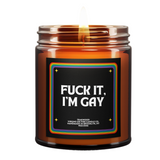 LGBTQ+ pride-themed candle in amber glass jar from Brooklyn-based Virgins on Fire, featuring bold text with rainbow border design. Handmade teakwood scented candle with inclusive messaging and pride flag emblem.