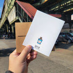 back of the pizza rat card. maker is holding it outside hte subway. the card has a photo of a rat in a coffee cup on it.