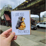"I Love You This Much" Pizza Rat Card. A big rat hugging a giant slice of pizza. the maker is holding the card outside the subway.
