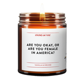 a burning candle called are you okay or are you female in america. amber glass jar. vanilla and orchid. 
