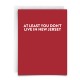 a red greeting card with white font that says "At Least You Don't Live in New Jersey." White Envelope Included.