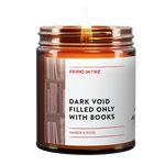 Bestselling funny candle 'Dark Void Filled Only With Books' candle featuring Amber & Rose scent. LGBTQ+-owned Virgins On Fire's humorous take on bookish candles. 9oz soy wax in amber jar. Handmade in Brooklyn, NY with minimalist design and book background imagery.