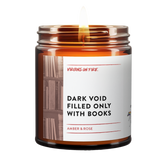 Bestselling funny candle 'Dark Void Filled Only With Books' candle featuring Amber & Rose scent. LGBTQ+-owned Virgins On Fire's humorous take on bookish candles. 9oz soy wax in amber jar. Handmade in Brooklyn, NY with minimalist design and book background imagery.