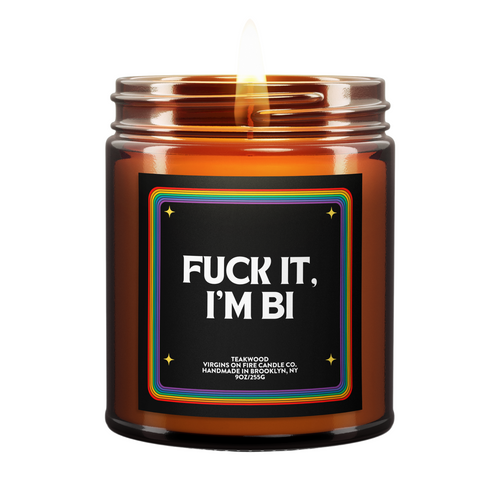 LGBTQ+ pride-themed candle in amber glass jar from Brooklyn-based Virgins on Fire, featuring bold text with rainbow border design. Handmade teakwood scented candle with inclusive messaging and pride flag emblem.