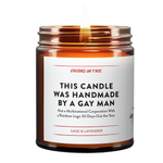 Amber glass candle jar with 'Best Seller' red badge. White label shows 'This Candle Was Handmade By a Gay Man' with subtitle about not being a multinational corporation. Sage & Lavender scent by Virgins on Fire company. Small pride mascot icon