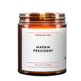 an amber jar candle that reads, "Madam President" it is dry gin and cypres scented. lit candle.
