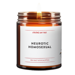 a burning candle. it is a brown amber jar. white label. black font. it says Neurotic Homosexual. red virgins on fire logo. red font that reads Sea Salt and Eucalyptus.