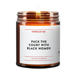 this candle is named "pack the court with black women". simple minimalist label. brown amber jar. lit. sea salt and orchid scented.