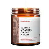 Candle jar with a label on a white background. Says Scatter my ashe son the A train. Cardamom and Cream. Photo of a train. Virgins On FIre Candle Co.