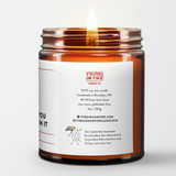 Back label of amber glass candle jar showing product details for Virgins On Fire Candle Co, a funny candle, gay-owned small business in Brooklyn, NY. 100% soy wax, handmade in Brooklyn, 45-50 hour burn time, non-toxic, 9oz size. Features Virgins on Fire Candle Co. branding, contact information, and cartoon flame mascot with rainbow flag. Includes a note about being handmade by a gay man rather than a corporation with a rainbow logo 30 days out of the year."