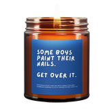 lit amber jar candle. blue background. it says, "some boys paint their nails, get over it." white eucalyptus scented.