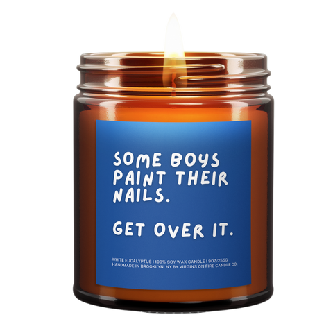 lit amber jar candle. blue background. it says, "some boys paint their nails, get over it." white eucalyptus scented.
