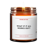 Candle in a glass jar with a label on a white background. the candle is called What If It all works out? vanilla and orchid scented from virgins on fire candle co, which is in red script font.