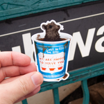 the maker holding the sticker in front of a subway station. a rat in a bodega cup of coffee - one of those We Are Happy To Serve You Greek style cups. Brown liquid everywhere. Funny and cute sticker.
