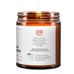 Back label of amber glass candle jar showing product details. 100% soy wax, handmade in Brooklyn, 45-50 hour burn time, non-toxic, 9oz size. Features Virgins on Fire Candle Co. branding, contact information, and cartoon mascot with rainbow flag. Includes note about being handmade by a gay man rather than a corporation with a rainbow logo 30 days out of the year."