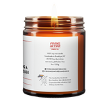 Back label of amber glass candle jar showing product details. 100% soy wax, handmade in Brooklyn, 45-50 hour burn time, non-toxic, 9oz size. Features Virgins on Fire Candle Co. branding, contact information, and cartoon mascot with rainbow flag. Includes note about being handmade by a gay man rather than a corporation."