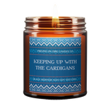 Winter-themed sweater style label. soy candle from Brooklyn's LGBTQ+-owned 'Virgins on Fire' featuring blue knit sweater pattern and text 'Keeping Up with the Cardigans', scented with Black Absinthe