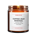 Best-selling amber glass funny candle from Virgins On Fire Candle Co., a gay-owned Brooklyn, NY small business. Label reads 'Cuffed Jean Bisexual' with subtitle 'Curled Up in a Weird Uncomfortable Chair With a Banned Book.' Cashmere and tonka scent.