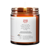 Back label of amber glass candle jar showing product details for Virgins On Fire Candle Co, a funny candle, gay-owned small business in Brooklyn, NY. 100% soy wax, handmade in Brooklyn, 45-50 hour burn time, non-toxic, 9oz size. Features Virgins on Fire Candle Co. branding, contact information, and cartoon flame mascot with rainbow flag. Includes a note about being handmade by a gay man rather than a corporation with a rainbow logo 30 days out of the year."