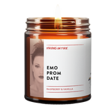 the emo prom date candle from virgins on fire candle co in brooklyn ny. raspberry and vanilla fragrance. safe fragrances and 100% soy wax. gay owned candlemaker. features emo looking girl under a red filter. lit candle. brown amber jar.