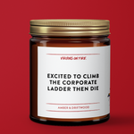 Gold Capped soy wax candle in brown amber jar with the text, "Excited to Climb the Corporate Ladder then die." Amber and Driftwood scent. From Virgins On Fire Candle Co., a gay-owned small business in Brooklyn, NY. Red background.