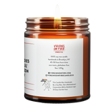 Back label of amber glass candle jar showing product details for Virgins On Fire Candle Co, a funny candle, gay-owned small business in Brooklyn, NY. 100% soy wax, handmade in Brooklyn, 45-50 hour burn time, non-toxic, 9oz size. Features Virgins on Fire Candle Co. branding, contact information, and cartoon flame mascot with rainbow flag. Includes a note about being handmade by a gay man rather than a corporation with a rainbow logo 30 days out of the year."