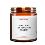 "Shut up let teachers teach" is a candle. this is a photo of it. lit. brown amber jar. it is tonka and oud scented.
