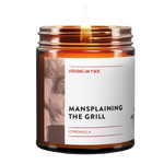 this is a brown amber jar candle with the text, "mansplaining the grill." it is a citronella candle. 