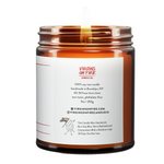 Back label of amber glass candle jar showing product details for Virgins On Fire Candle Co, a funny candle, gay-owned small business in Brooklyn, NY. 100% soy wax, handmade in Brooklyn, 45-50 hour burn time, non-toxic, 9oz size. Features Virgins on Fire Candle Co. branding, contact information, and cartoon flame mascot with rainbow flag. Includes a note about being handmade by a gay man rather than a corporation with a rainbow logo 30 days out of the year."